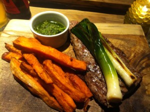 Steak with chimichurri sauce, sweet potato fries and grilled baby leeks